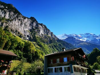 Houses by mountain against clear blue sky