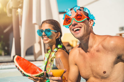 Portrait of shirtless young woman wearing sunglasses while standing in city