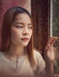 Close-up portrait of young woman touching window and look through ,vintage style