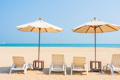 Deck chairs on beach against clear sky