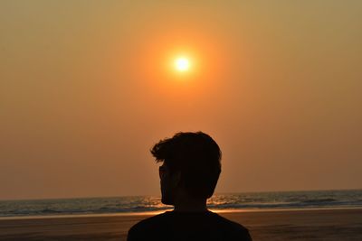 Rear view of silhouette man at beach during sunset