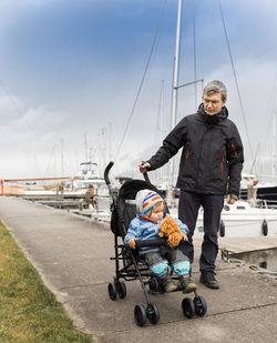 Grandfather with granddaughter in baby carriage at harbor