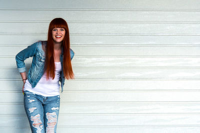 Portrait of young woman standing against wall
