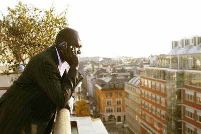 Side view of man using mobile phone against sky