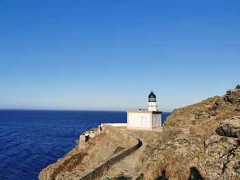 Lighthouse by sea against clear sky