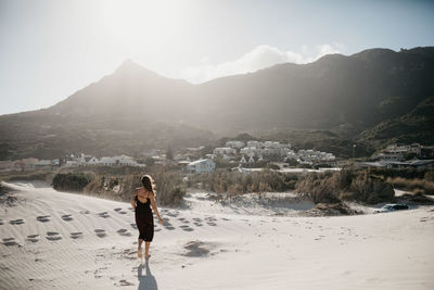 Rear view of woman standing on land against sky