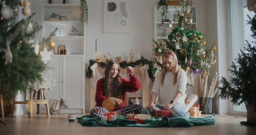 Rear view of woman with christmas tree at home