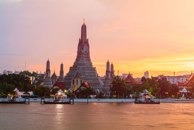 Temple by building against sky during sunset