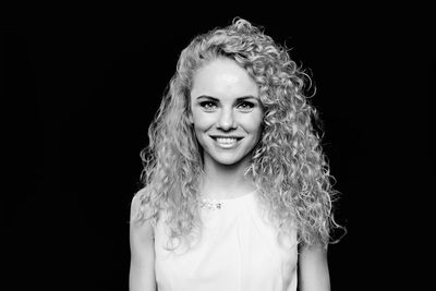 Portrait of smiling woman against black background