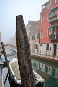 Close-up of wooden post against buildings in city