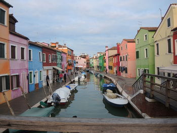 Boats in canal amidst buildings in city against sky