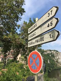 Information sign by road against sky