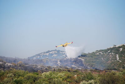 Airplane flying over mountains against clear blue sky