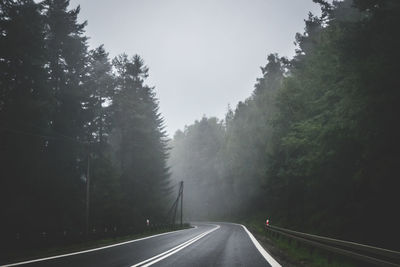 Empty road amidst trees against sky