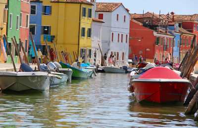 Boats moored in canal amidst buildings in city