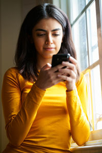 Young woman using mobile phone at home