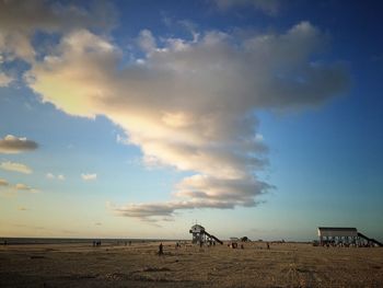 People at beach against cloudy sky