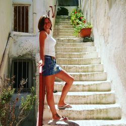 Full length portrait of happy young woman on steps