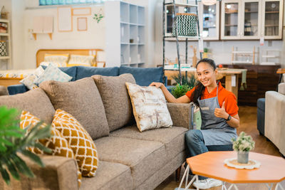 Young woman using phone while sitting on sofa at home