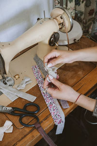 Cropped hand of woman using sewing machine