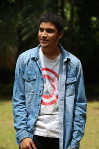 Side view of young men standing against trees