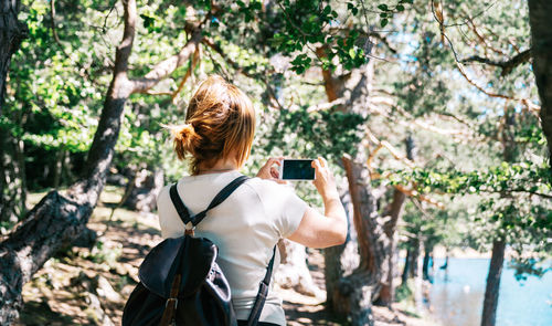 Rear view of woman photographing through mobile phone