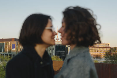 Lesbian couple face to face against famous communications tower in city