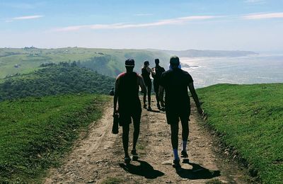 Rear view of people walking on mountain towards sea