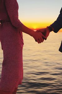 Couple holding hands infront of sunset