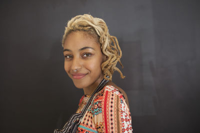 Portrait of smiling woman standing against wall