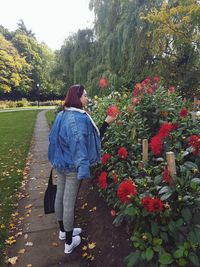 Rear view of woman standing on footpath amidst flowering plants