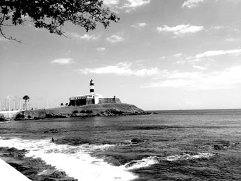 Lighthouse in sea against sky