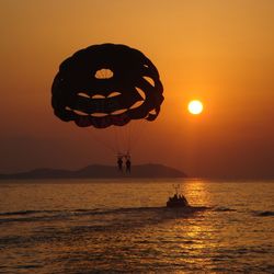 Silhouette people by sea against sky during sunset