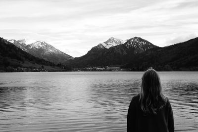 Rear view of woman looking at lake against mountains