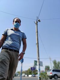 Low angle view of man with protective face mask against clear sky