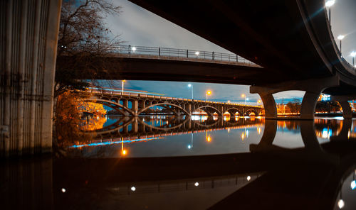 Low angle view of illuminated bridge over river at night