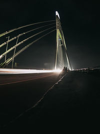 Light trails on bridge against sky at night