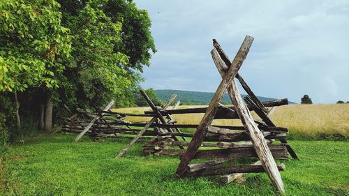 Wooden posts on field against sky