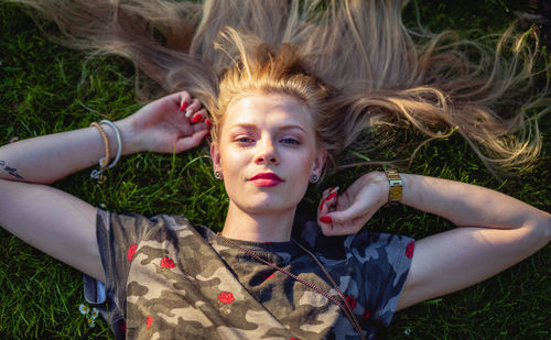 High angle portrait of young woman lying on grassy field