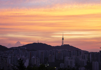 Buildings in city against sky during sunset