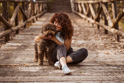 Woman embracing dog on boardwalk