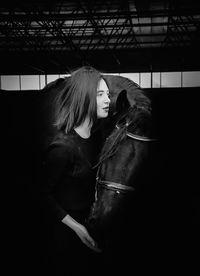 Side view of woman standing with horse in darkroom