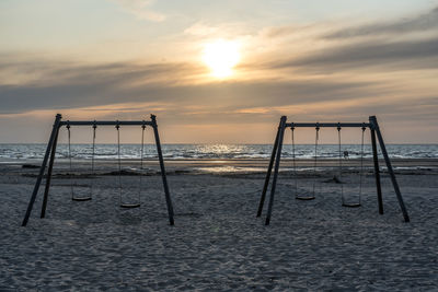 Lifeguard hut on beach against sky during sunset