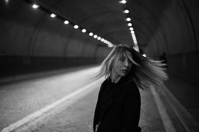 Portrait of woman standing against illuminated light at night