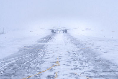 Airplane on snow covered land against sky