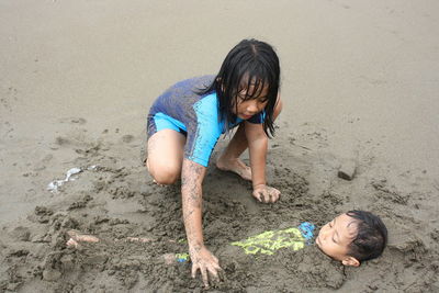 High angle view of boy playing with sand at beach