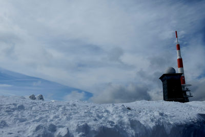 Tower on snow covered mountain against sky