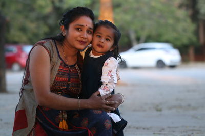 Portrait of mother embracing daughter on road