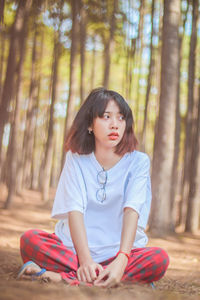 Portrait of a smiling young woman sitting in the forest