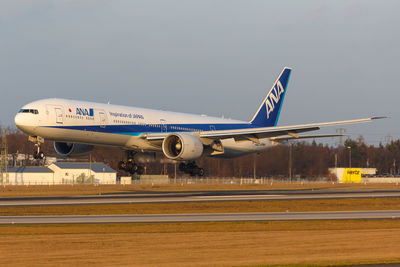 Airplane flying over airport runway against sky